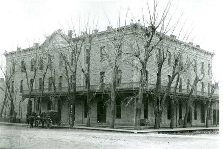 A historic stone building with bare trees and a horse-drawn carriage in front.