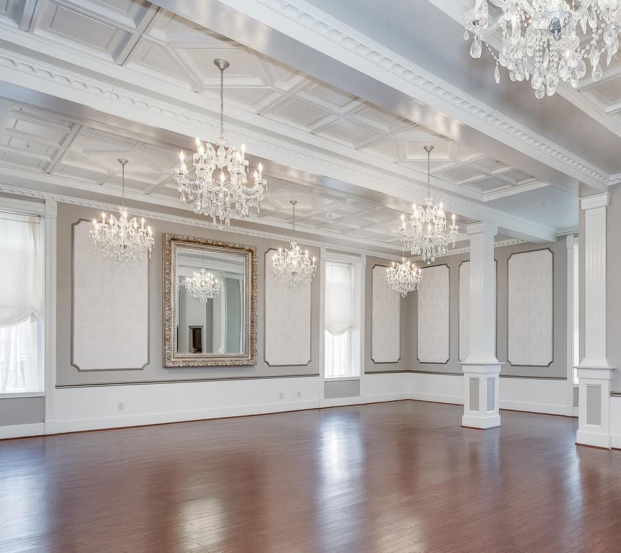 A spacious and elegantly decorated room with crystal chandeliers and a large decorative mirror.