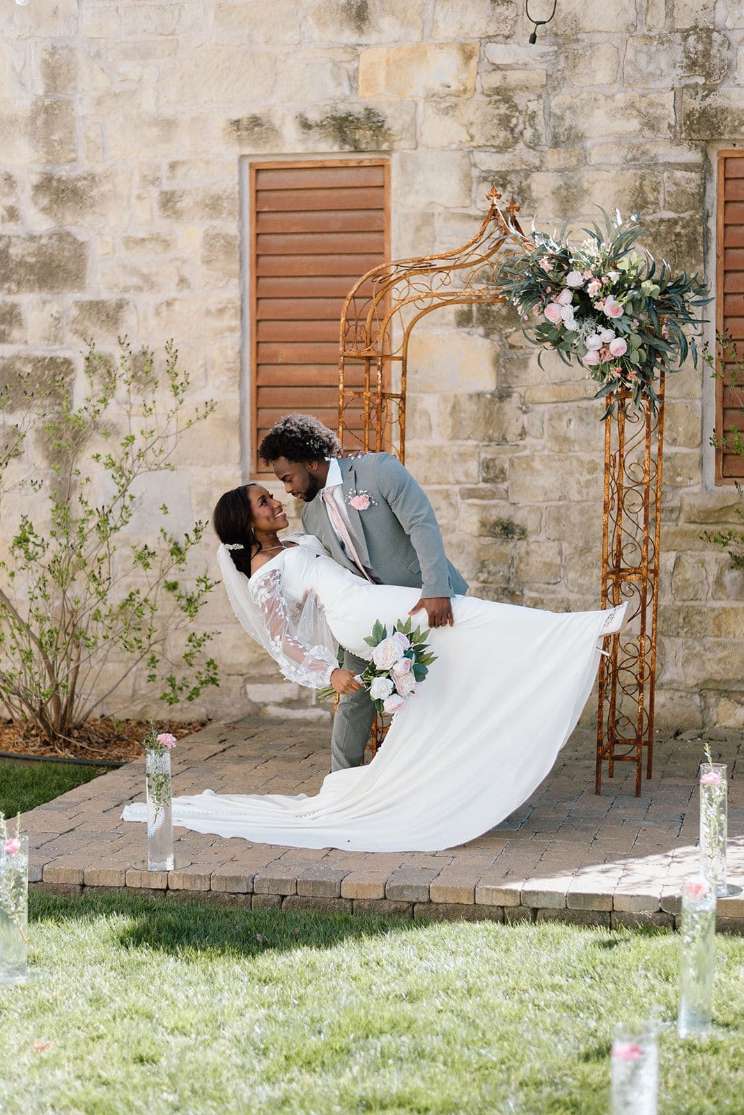 A couple shares a romantic moment during their wedding ceremony, framed by a floral arch.