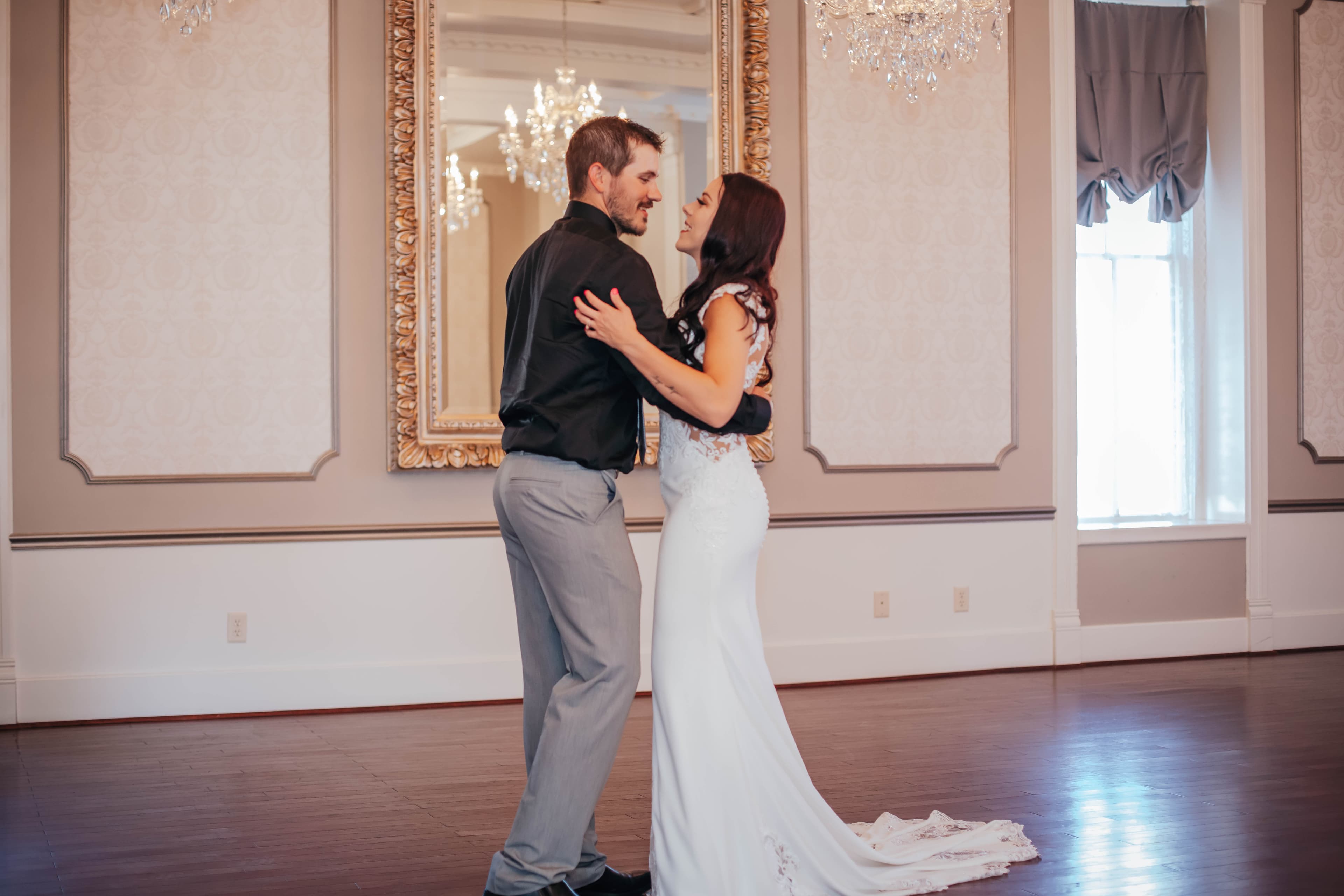 A couple shares a joyful moment while dancing in an elegant indoor setting.