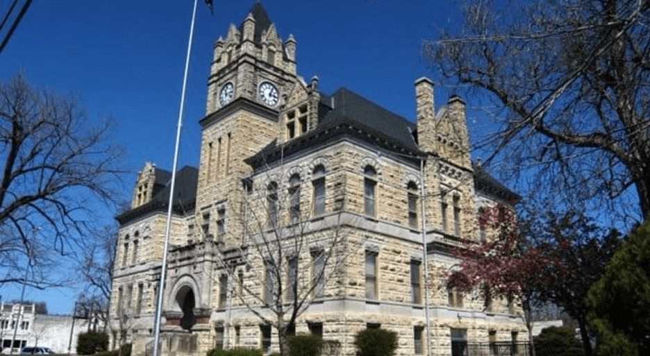 Historic stone courthouse with a clock tower against a clear blue sky.