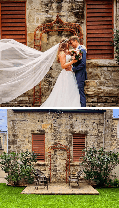 A couple embraces under a flowing veil in front of a stone wall, with an outdoor seating area visible below.
